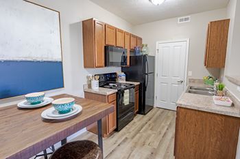 A kitchen with a refrigerator, microwave, oven, and sink.